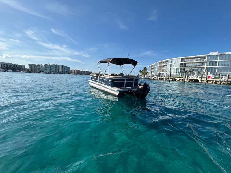 Slide: The Image of 2021 Godfrey Sweetwater pontoon boat on clear blue water near modern buildings. - 4