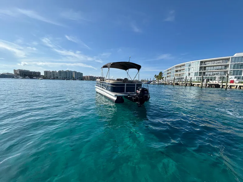 Slide: The Image of 2021 Godfrey Sweetwater pontoon boat on clear blue water near modern waterfront buildings. - 6