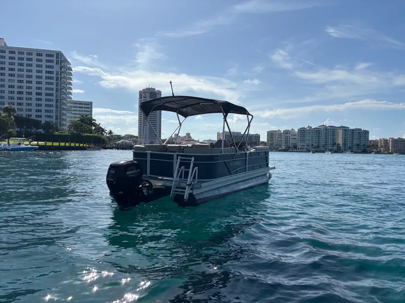 Slide: The Image of 2021 Godfrey Sweetwater pontoon boat on a sunny waterfront with city skyline. - 7