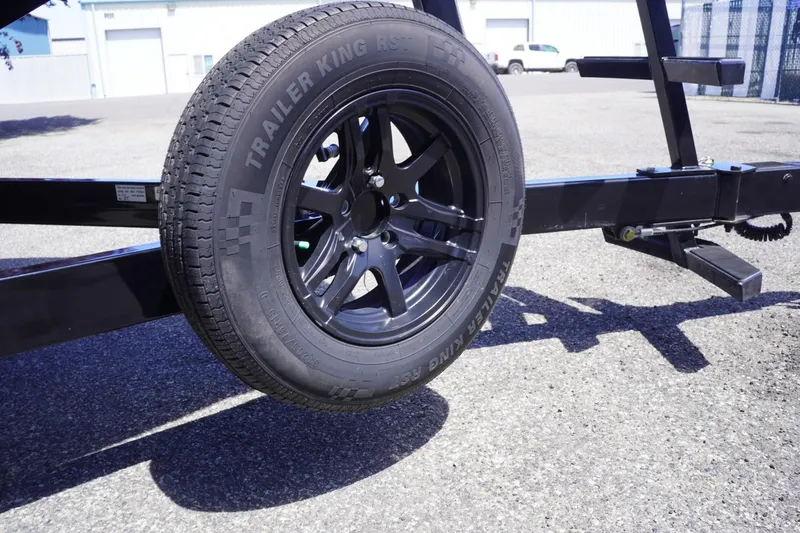 Slide: The Image of Trailer wheel of a 2023 Tigé 23ZX boat trailer on asphalt surface. - 13