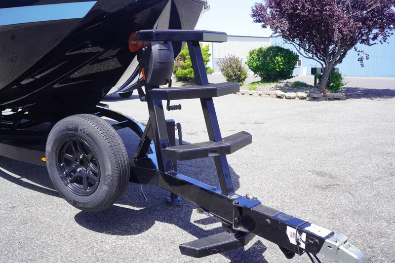 Slide: The Image of 2023 Tigé 23ZX boat trailer with black steps and wheel, parked outdoors. - 14