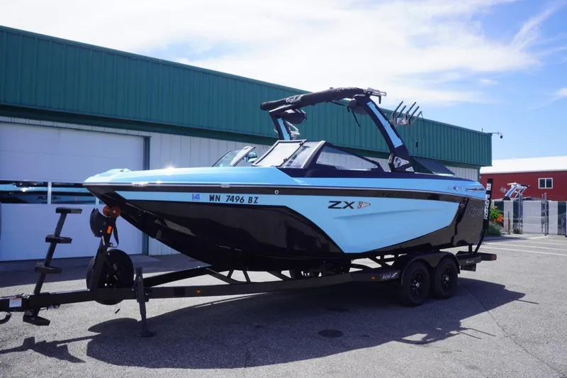 Slide: The Image of 2023 Tigé 23ZX boat on trailer, parked outdoors near green building. - 16