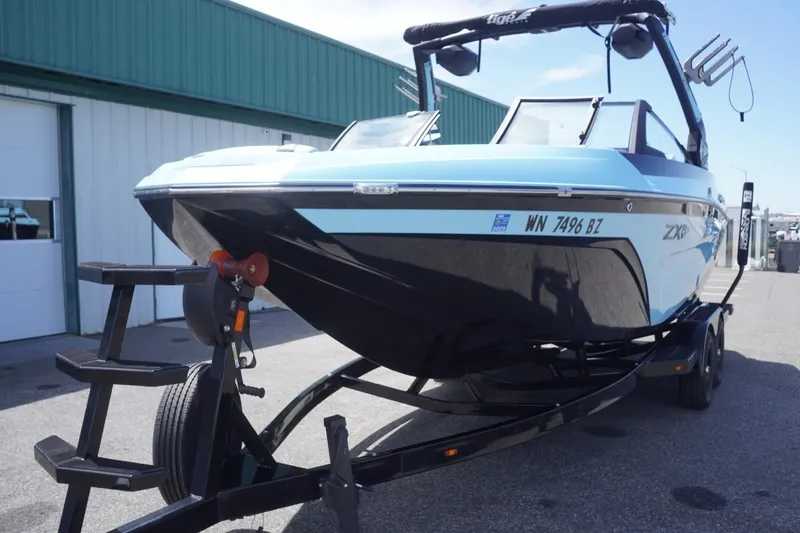 Slide: The Image of 2023 Tigé 23ZX boat on trailer, blue and black design, parked outdoors. - 17
