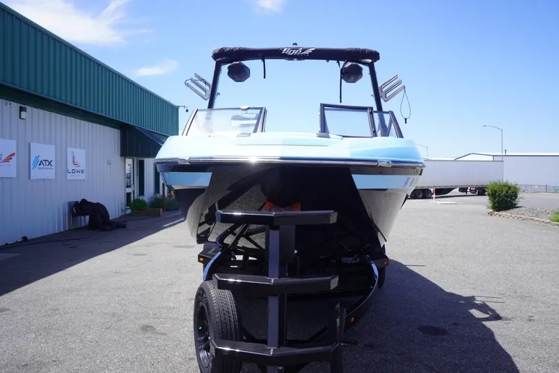 Slide: The Image of 2023 Tigé 23ZX boat on trailer, parked outside a building under clear blue sky. - 18