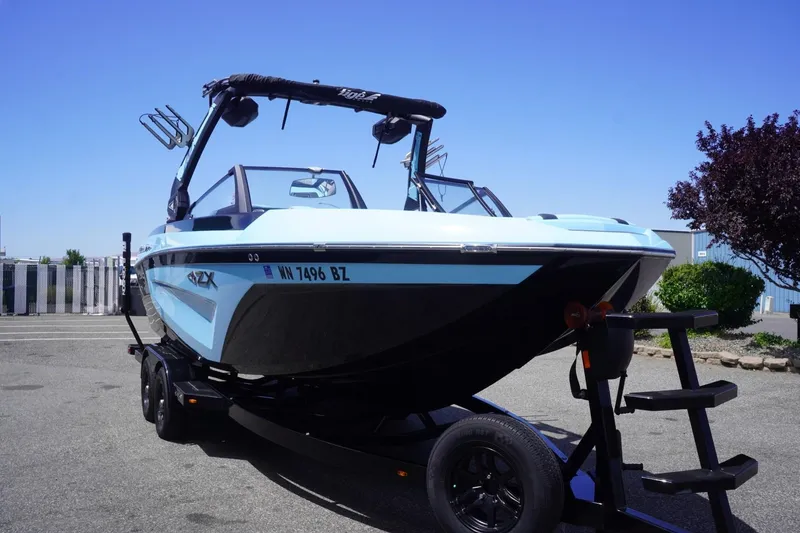 Slide: The Image of 2023 Tigé 23ZX boat on trailer, parked outdoors under clear blue sky. - 19