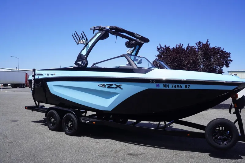Slide: The Image of 2023 Tigé 23ZX boat on trailer, blue and black design, parked outdoors. - 20