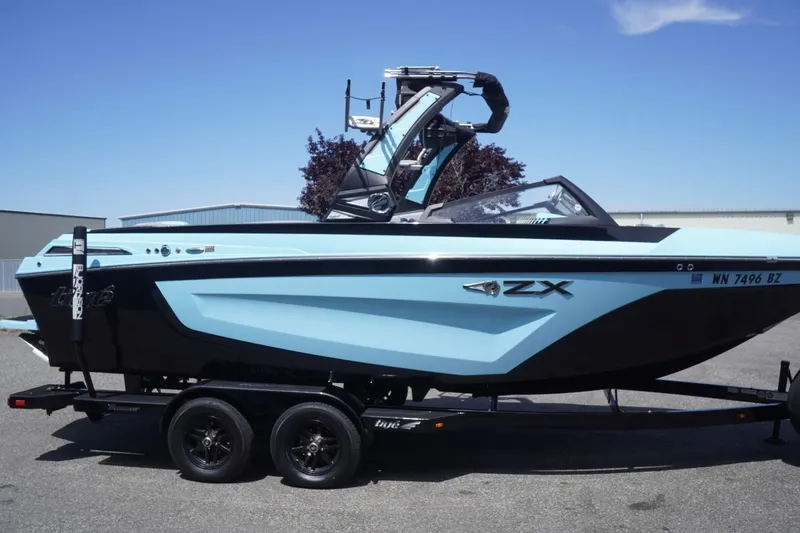 Slide: The Image of 2023 Tigé 23ZX boat in light blue and black on a trailer, parked outdoors. - 21