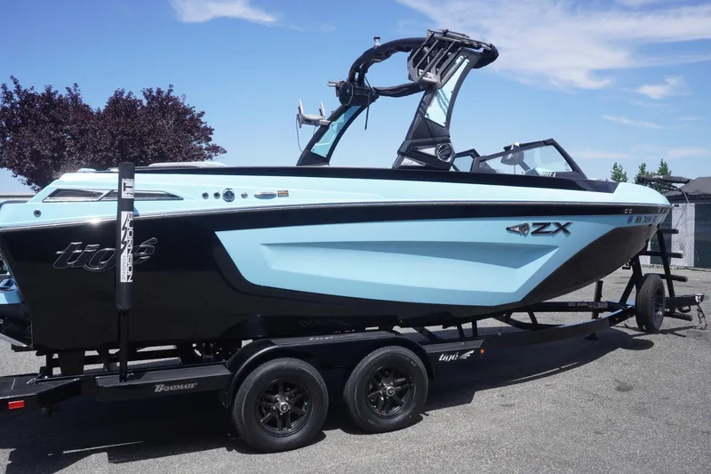 Slide: The Image of 2023 Tigé 23ZX boat on trailer, featuring sleek black and blue design. - 22