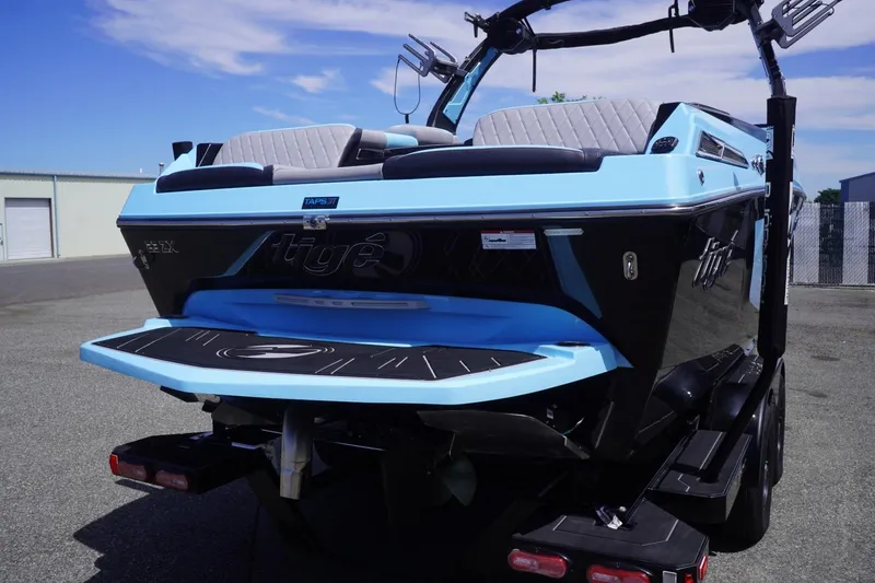 Slide: The Image of 2023 Tigé 23ZX boat, blue and black, parked on pavement under clear sky. - 24
