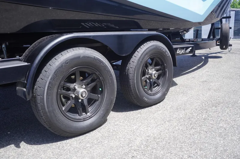 Slide: The Image of 2023 Tigé 23ZX boat trailer with black wheels on pavement. - 3