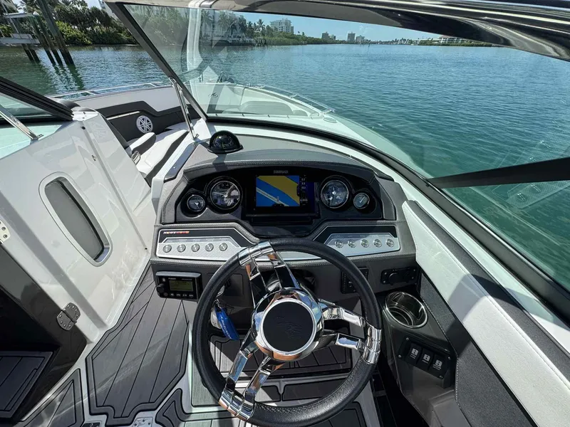 Slide: The Image of 2023 Monterey 275SS boat dashboard with steering wheel and navigation system on a sunny day. - 10