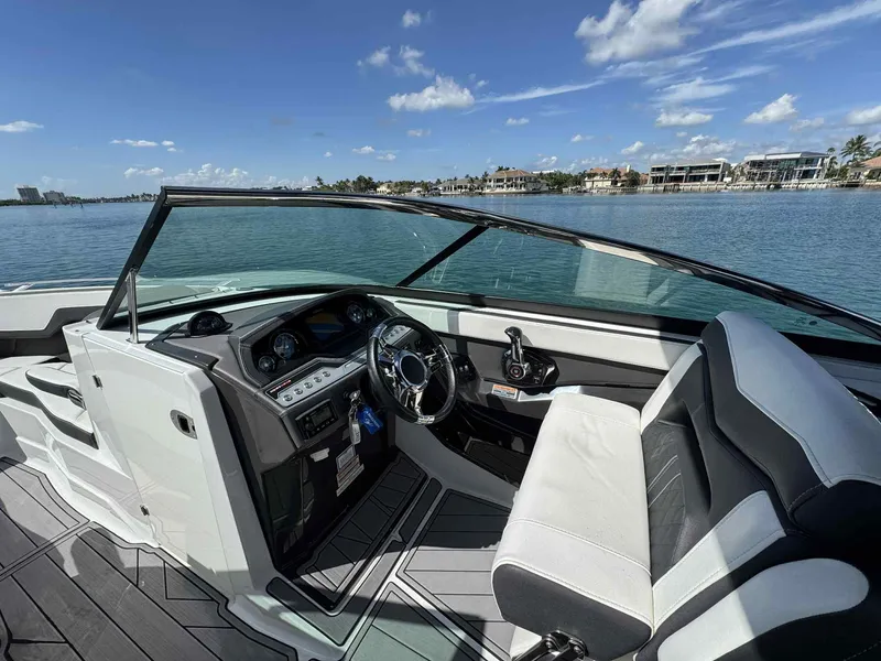 Slide: The Image of 2023 Monterey 275SS boat interior with steering wheel, dashboard, and seating, overlooking calm waters. - 11
