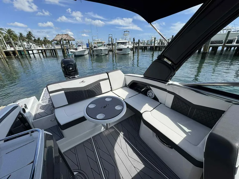 Slide: The Image of 2023 Monterey 275SS boat interior with seating and table, docked at a marina under blue skies. - 23