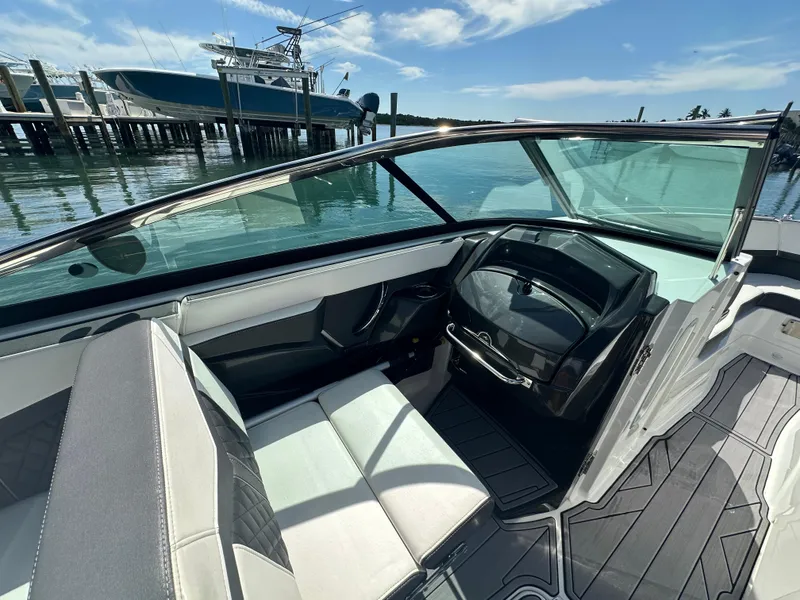 Slide: The Image of 2023 Monterey 275SS boat interior with sleek seating and modern dashboard, docked by the water. - 6