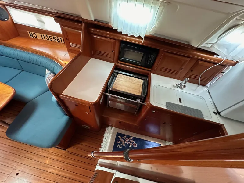 Slide: The Image of Interior of 2002 Beneteau 411 yacht, featuring kitchen area with stove, sink, and seating. - 30