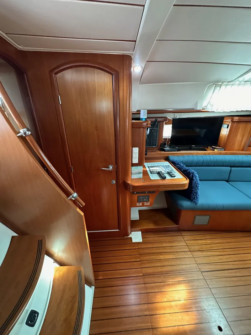 Slide: The Image of Interior of 2002 Beneteau 411 sailboat with wooden flooring and blue seating. - 40