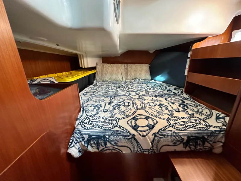 Slide: The Image of Cozy cabin interior of 2002 Beneteau 411 sailboat with patterned bedding and wooden shelves. - 43
