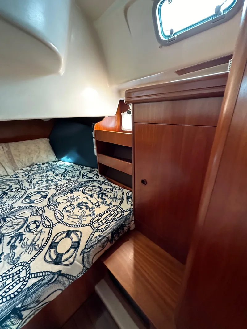 Slide: The Image of Cozy cabin interior of 2002 Beneteau 411 sailboat with wooden furnishings and patterned bedding. - 44