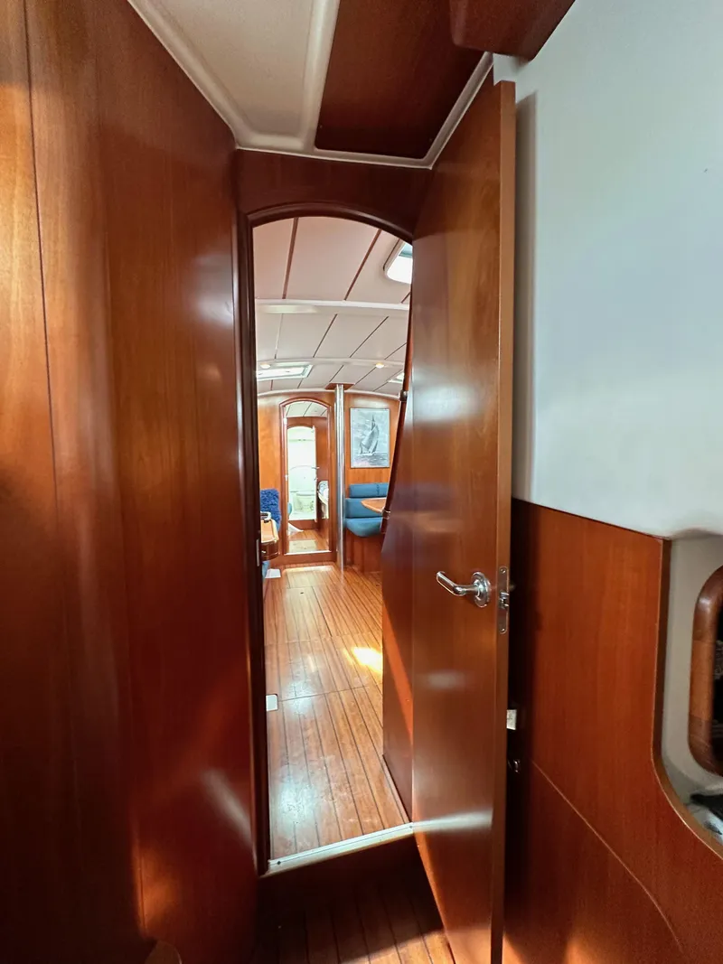 Slide: The Image of Interior view of 2002 Beneteau 411 sailboat with wooden finish and open cabin door. - 45