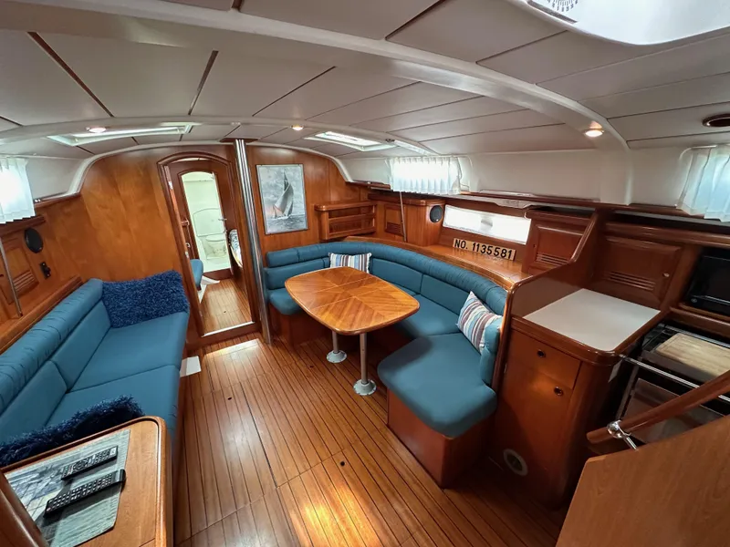Slide: The Image of Interior of a 2002 Beneteau 411 sailboat with wooden flooring and blue seating. - 46