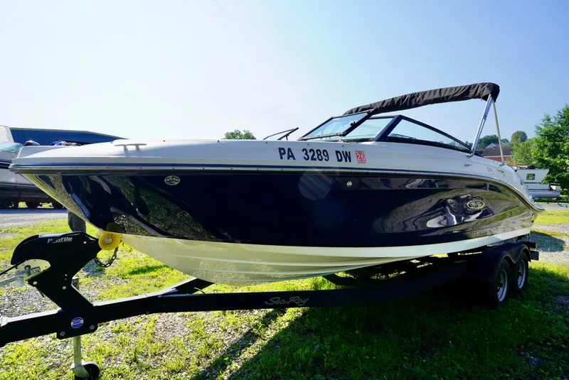Slide: The Image of 2018 Sea Ray SPX 230 boat on trailer, parked outdoors in sunny setting. - 2