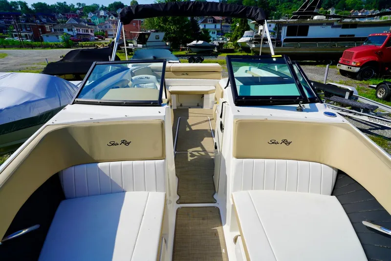 Slide: The Image of 2018 Sea Ray SPX 230 boat interior with beige seating and windshield, docked outdoors. - 22