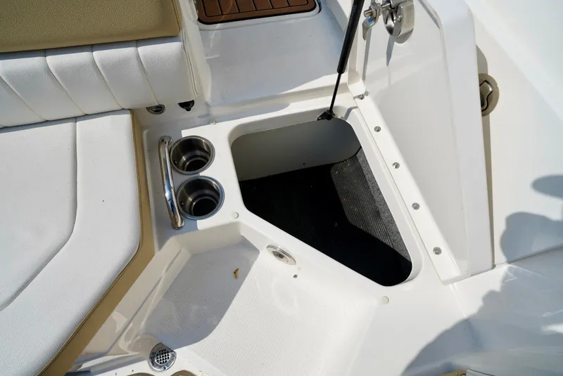 Slide: The Image of 2018 Sea Ray SPX 230 boat interior with open storage compartment and cup holders. - 25