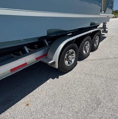 Slide: The Image of 2018 Scout 355 LXF boat on trailer, side view, under clear blue sky. - 10