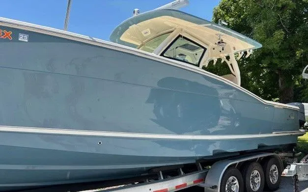 Slide: The Image of 2018 Scout 355 LXF boat on trailer, front view, outdoors under clear blue sky. - 15