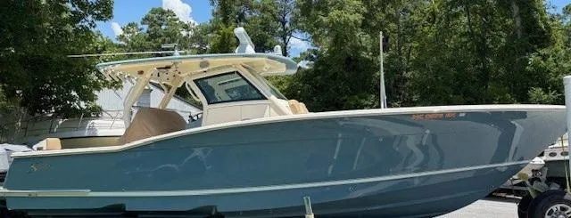 Slide: The Image of 2018 Scout 355 LXF boat on trailer under clear blue sky. - 18