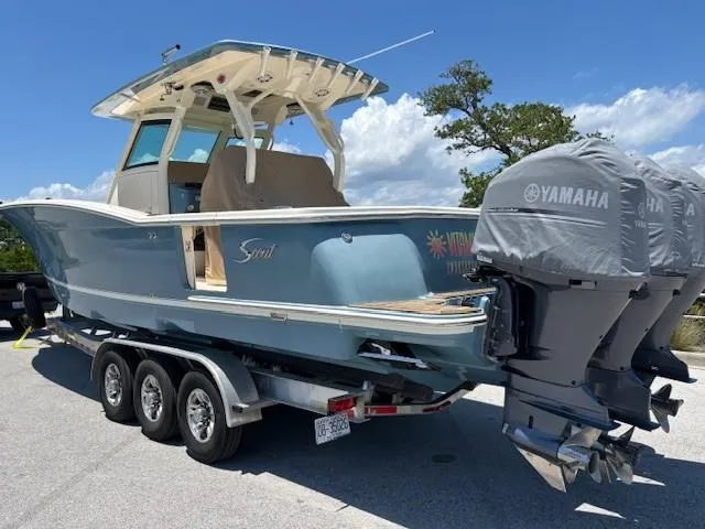 Slide: The Image of 2018 Scout 355 LXF boat on trailer under clear blue sky. - 2