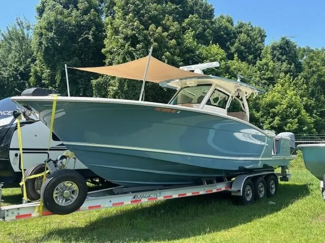 Slide: The Image of 2018 Scout 355 LXF boat on a triple-axle trailer, parked on pavement. - 20