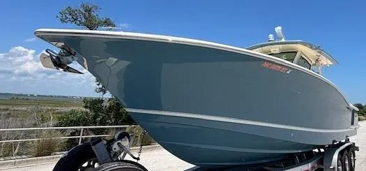Slide: The Image of 2018 Scout 355 LXF boat with sleek design and chrome logo in sunlight. - 9