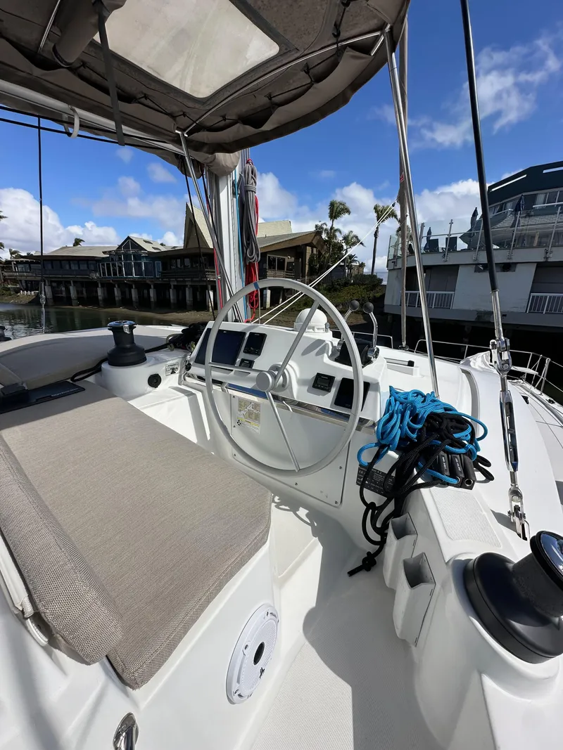 Slide: The Image of 2023 Bali 4.2 yacht cockpit with steering wheel, ropes, and seating, docked at marina. - 11
