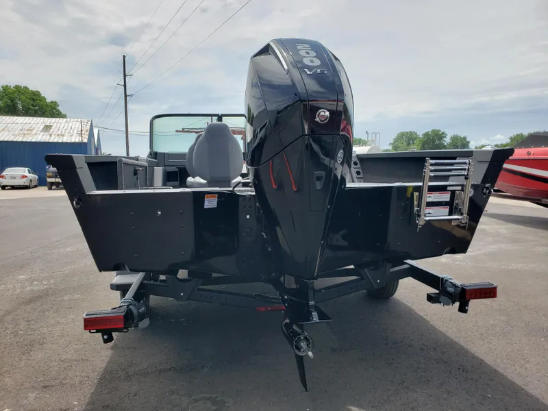 Slide: The Image of 2025 Alumacraft Competitor 185X Sport boat with powerful outboard motor, parked outdoors. - 2