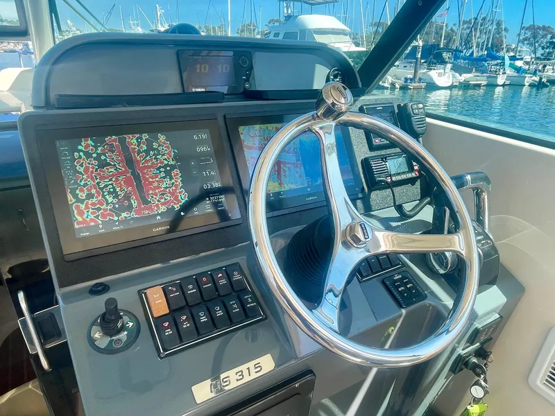 Slide: The Image of Control panel of a 2011 Pursuit 315 Offshore boat with navigation screens and steering wheel. - 15