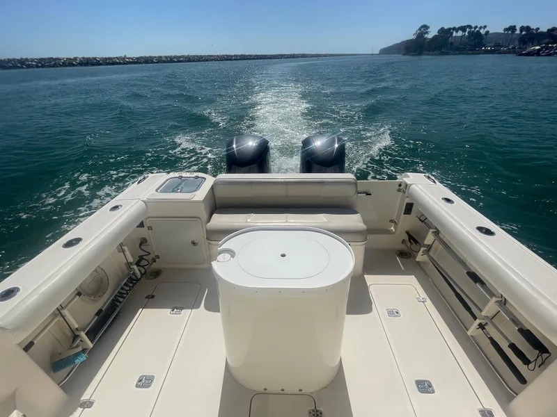 Slide: The Image of 2011 Pursuit 315 Offshore boat cruising on open water, showcasing spacious deck and twin engines. - 18