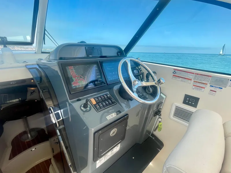 Slide: The Image of 2011 Pursuit 315 Offshore boat helm with navigation screens and steering wheel, ocean view. - 20