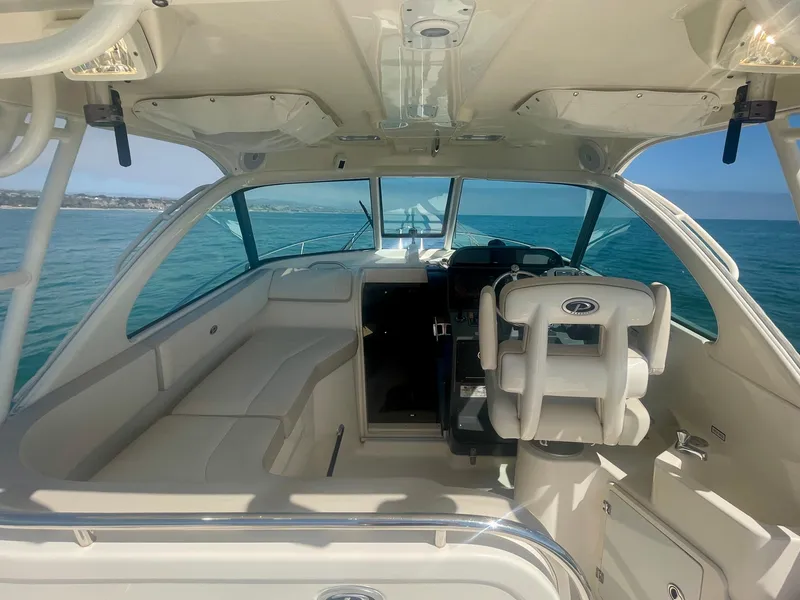 Slide: The Image of 2011 Pursuit 315 Offshore boat interior with helm and seating, cruising on open water. - 24