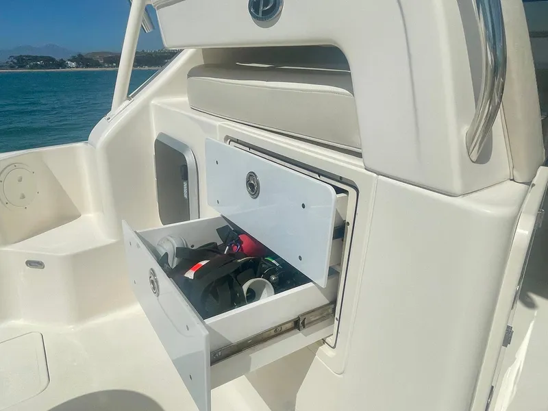Slide: The Image of 2011 Pursuit 315 Offshore boat storage compartment with open drawer, ocean view in background. - 26