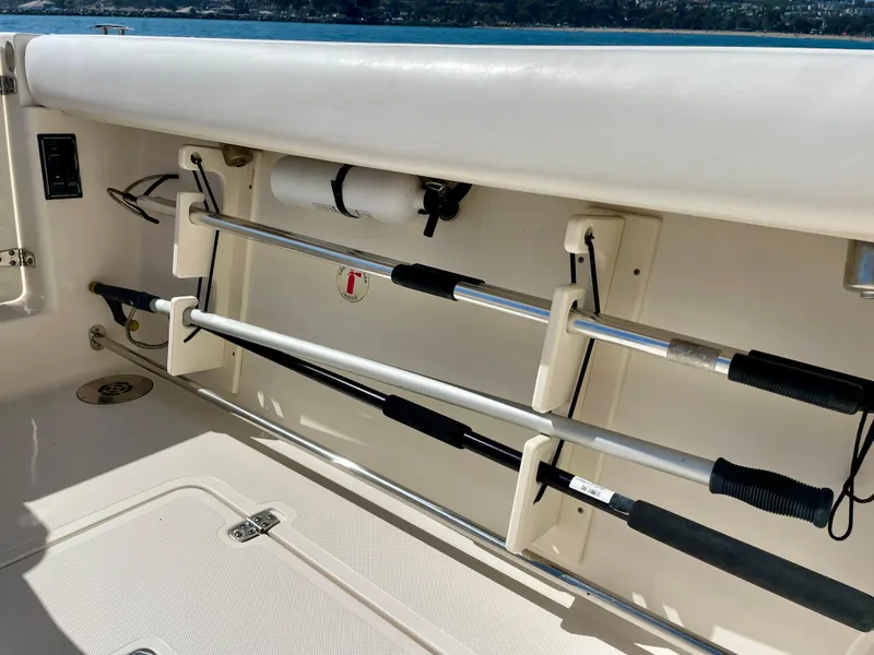 Slide: The Image of 2011 Pursuit 315 Offshore boat interior with fishing rod holders and storage compartment. - 28