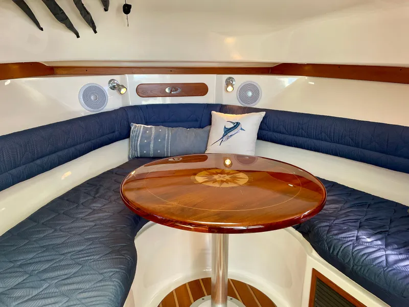 Slide: The Image of 2011 Pursuit 315 Offshore cabin with blue seating and wooden table. - 39
