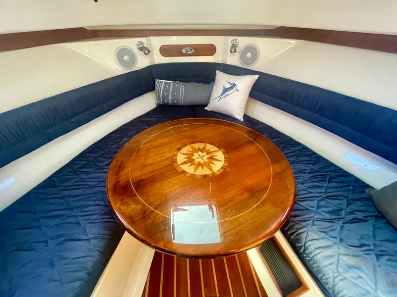 Slide: The Image of 2011 Pursuit 315 Offshore cabin with wooden table and cushioned seating. - 44