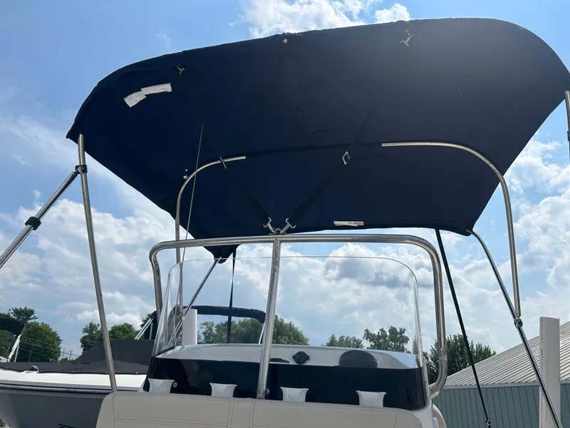 Slide: The Image of 2018 Boston Whaler 150 Montauk with blue bimini top under a cloudy sky. - 5