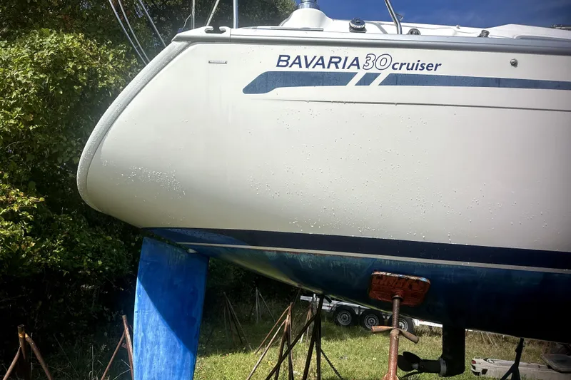 Slide: The Image of 2007 Bavaria 30 Cruiser sailboat on land, side view with visible keel and logo. - 17