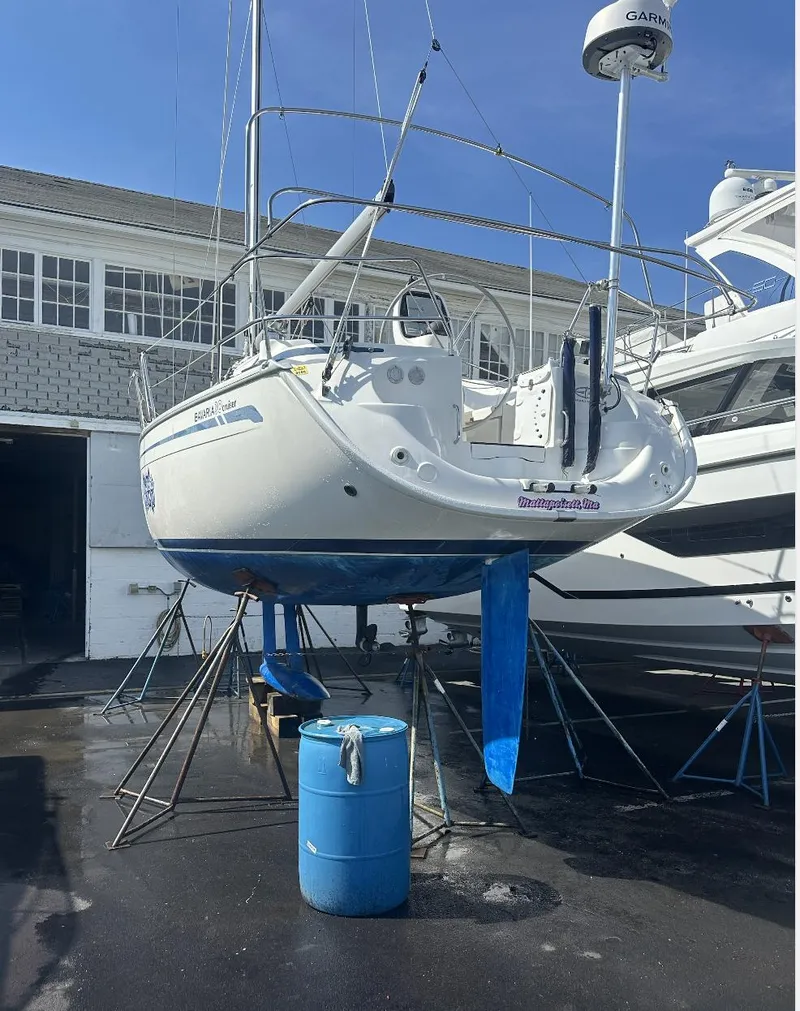 Slide: The Image of 2007 Bavaria 30 Cruiser sailboat on stands, with blue hull, near a building. - 9