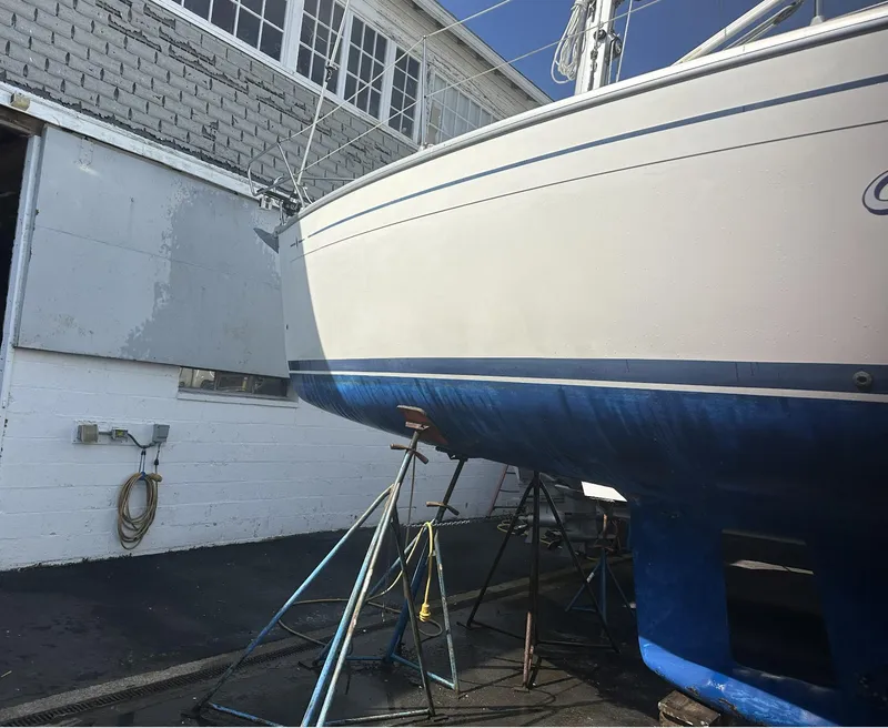 Slide: The Image of 2007 Bavaria 30 Cruiser sailboat on stands, undergoing maintenance near a building. - 7