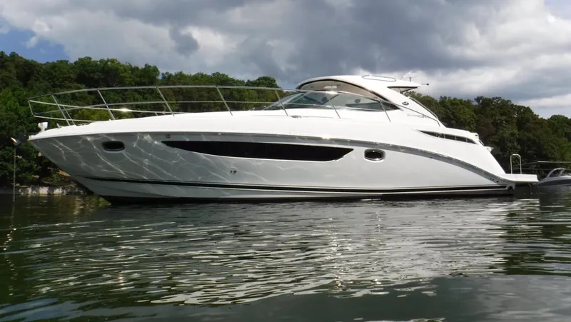 The Image of 2014 Sea Ray 410 Sundancer yacht on calm water, surrounded by lush greenery. - 0