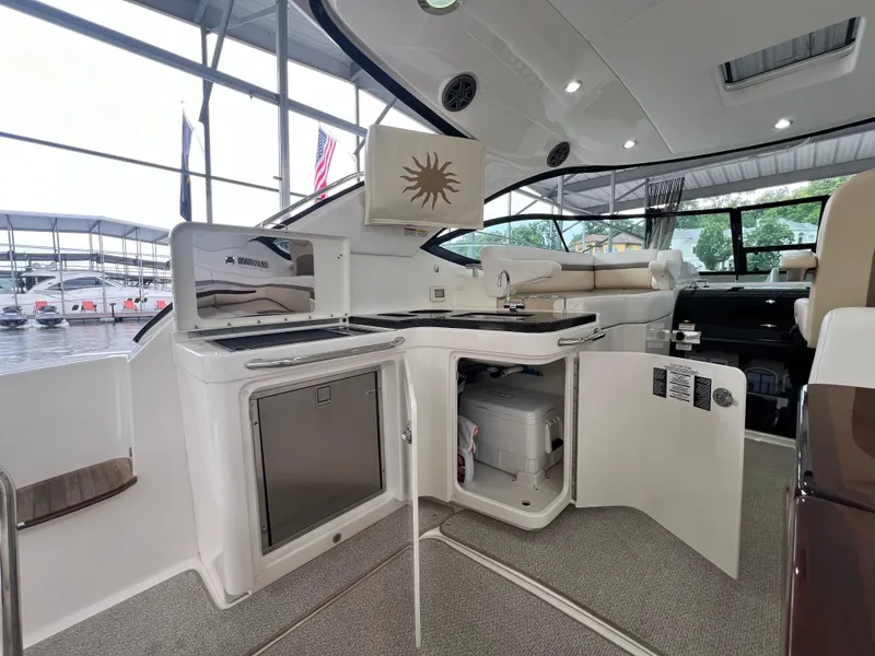 Slide: The Image of 2014 Sea Ray 410 Sundancer yacht interior with kitchenette and seating area. - 18