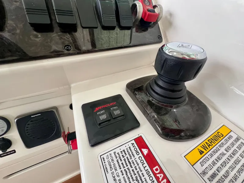 Slide: The Image of Control panel of a 2014 Sea Ray 410 Sundancer boat with joystick and warning labels. - 26